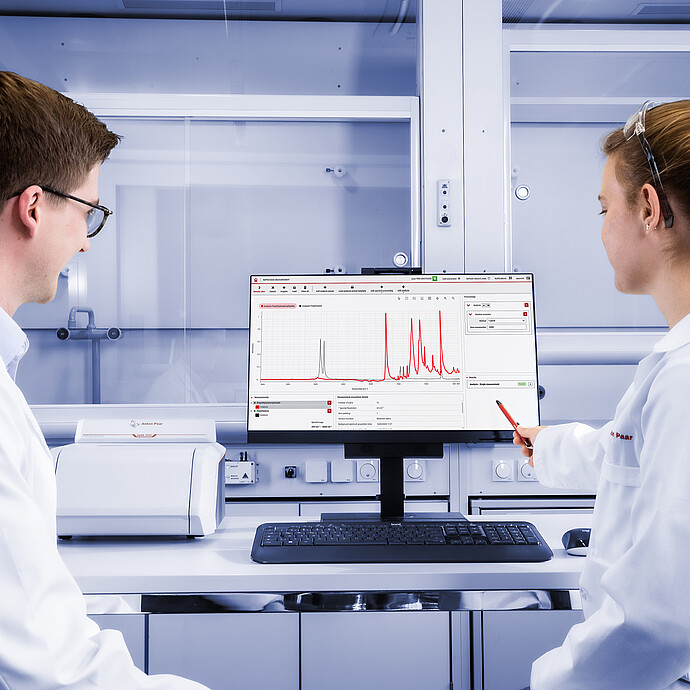 两名实验人员正在操作放置在显示器前的 Lyza 3000 FTIR 光谱仪,显示器上显示着 Spectroscopy Suite 光谱分析软件